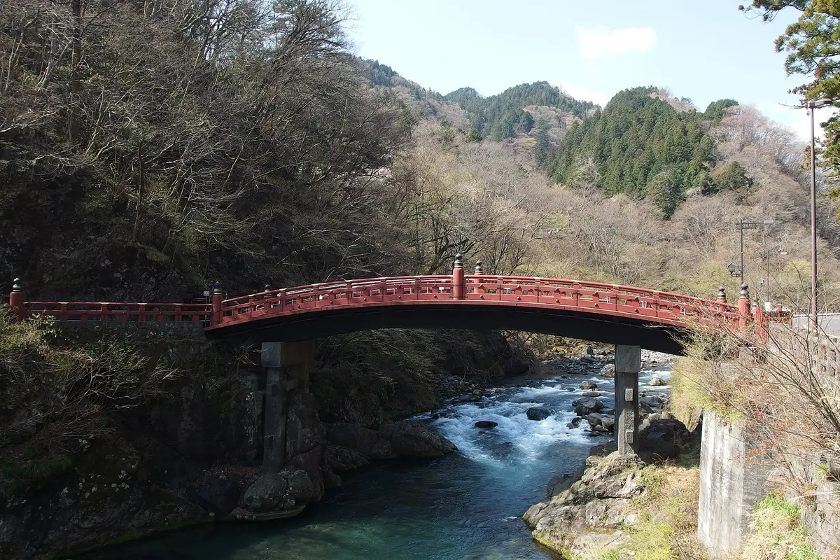 El pont vermell en arc de Shinkyo travessa el riu verd Daiya en una vall boscosa de Nikko