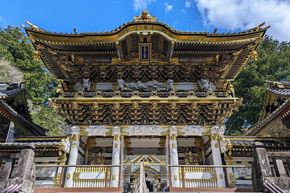 La porta Yomeimon del santuari Toshogu de Nikko, una porta de dos pisos coberta de full d'or, amb dracs i lleons esculpits, vista des de les escales de sota